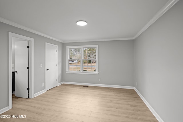 empty room featuring light hardwood / wood-style floors and crown molding