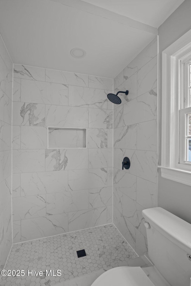 bathroom featuring a tile shower and toilet