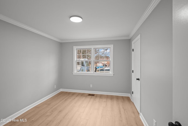 empty room with crown molding and light hardwood / wood-style floors