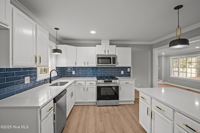 kitchen with sink, hanging light fixtures, white cabinets, and stainless steel appliances