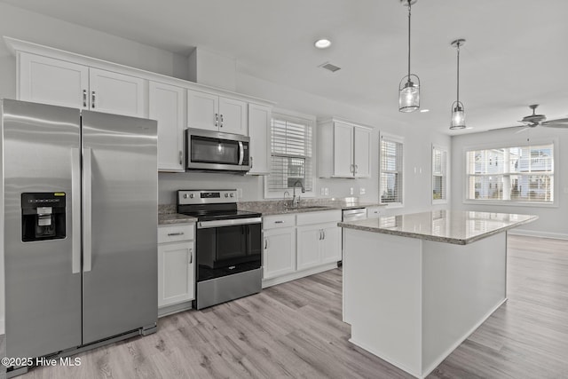 kitchen with sink, decorative light fixtures, a center island, appliances with stainless steel finishes, and white cabinets