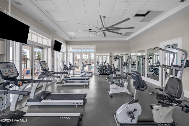 exercise room with a paneled ceiling, ceiling fan, and french doors