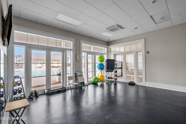 exercise room with french doors, a paneled ceiling, and a high ceiling