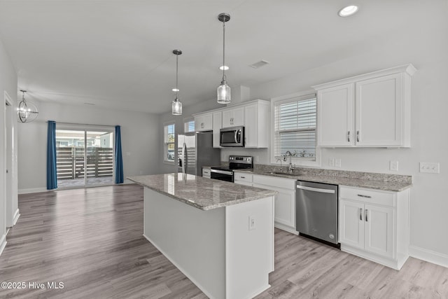 kitchen featuring sink, white cabinetry, light stone counters, a center island, and appliances with stainless steel finishes