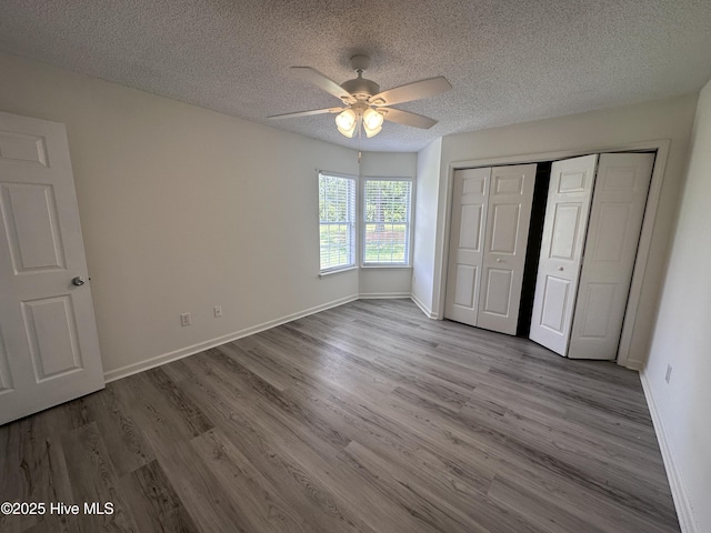 unfurnished bedroom featuring ceiling fan, light wood-type flooring, a textured ceiling, and a closet