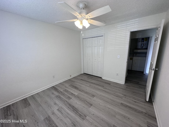 unfurnished bedroom with ceiling fan, independent washer and dryer, a textured ceiling, a closet, and hardwood / wood-style flooring