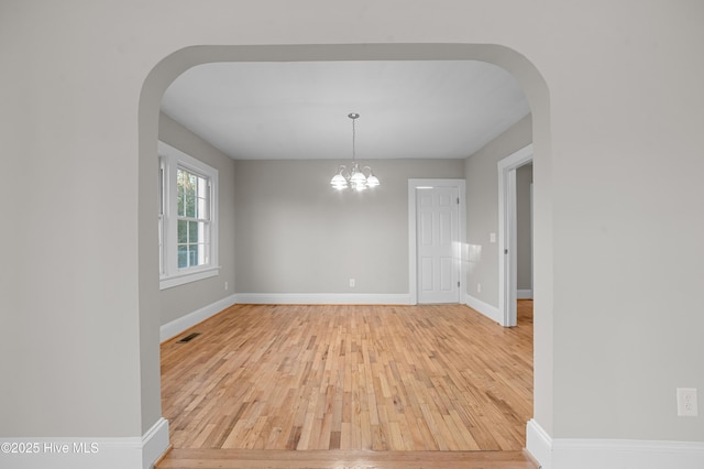 spare room with light wood-type flooring and an inviting chandelier