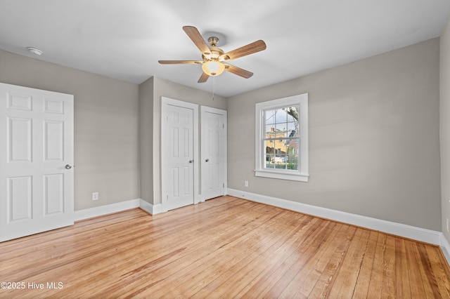 unfurnished bedroom with ceiling fan, light hardwood / wood-style floors, and two closets