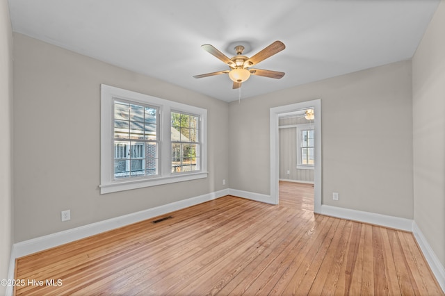 empty room with ceiling fan, a healthy amount of sunlight, and light wood-type flooring