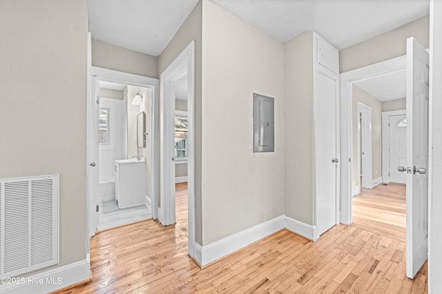 corridor featuring electric panel and light hardwood / wood-style flooring