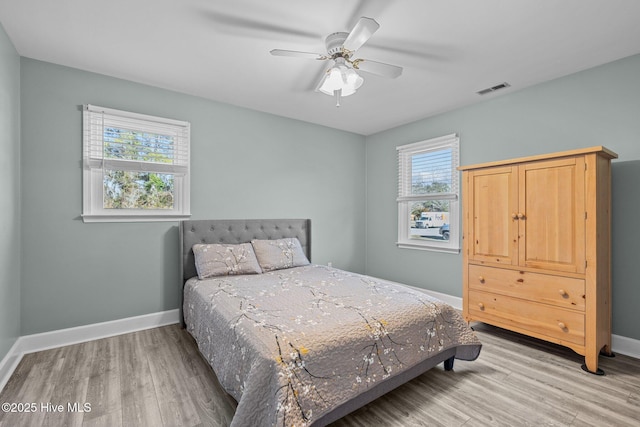 bedroom featuring multiple windows, light hardwood / wood-style floors, and ceiling fan