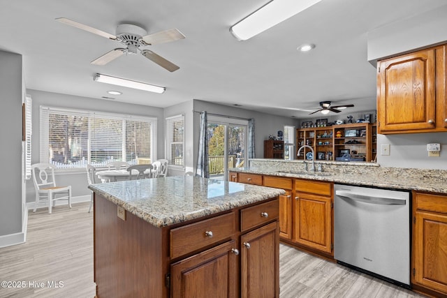 kitchen with stainless steel dishwasher, light stone countertops, sink, and light wood-type flooring