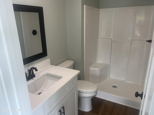 bathroom with hardwood / wood-style floors, vanity, toilet, and walk in shower