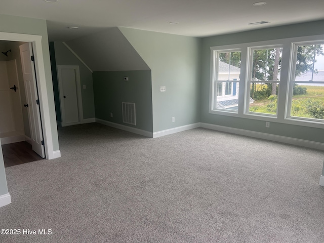 bonus room with light colored carpet and vaulted ceiling