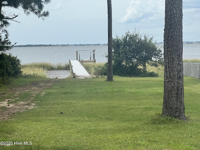 view of dock with a lawn and a water view