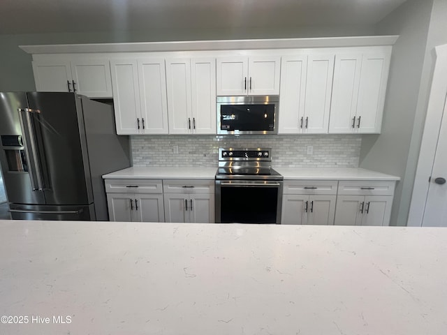 kitchen with white cabinetry, stainless steel appliances, and tasteful backsplash