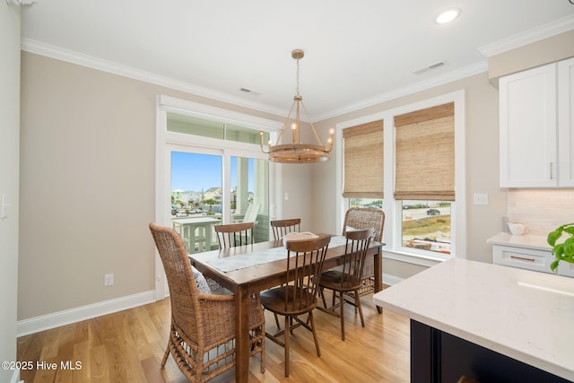 dining area featuring light hardwood / wood-style floors, an inviting chandelier, and crown molding