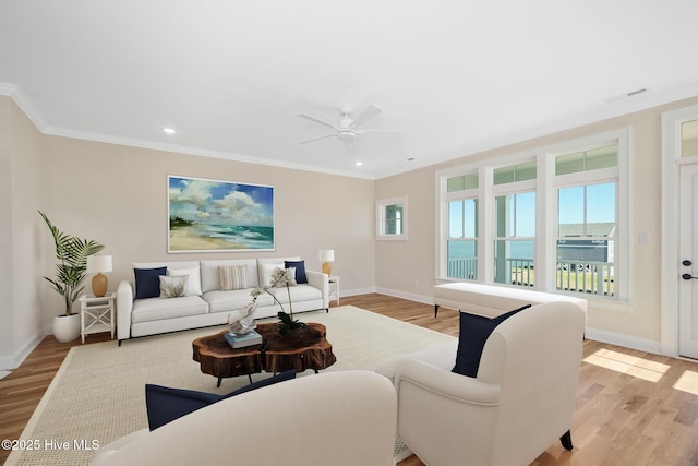 living room with a water view, ornamental molding, and light hardwood / wood-style flooring