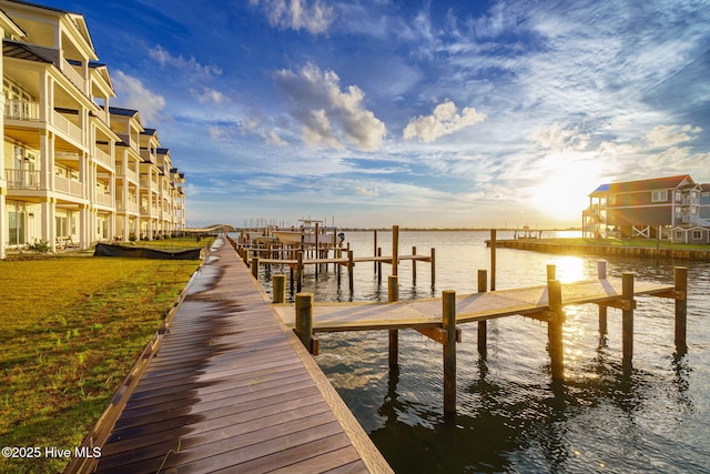 view of dock with a lawn and a water view