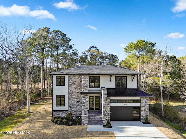 view of front facade with driveway, stone siding, metal roof, an attached garage, and a standing seam roof