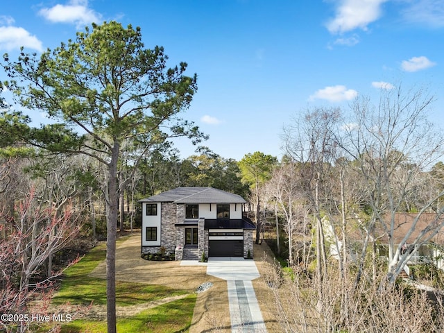 view of front of house with a garage, a front yard, stone siding, and driveway