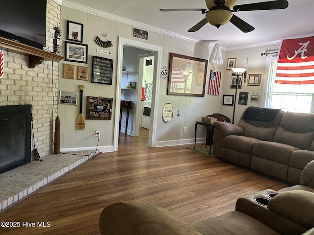 living room featuring a fireplace, hardwood / wood-style flooring, ceiling fan, and crown molding