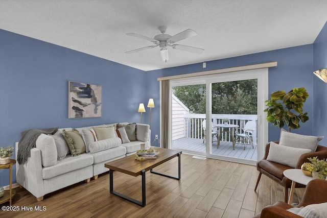 living room featuring ceiling fan, wood-type flooring, and a textured ceiling