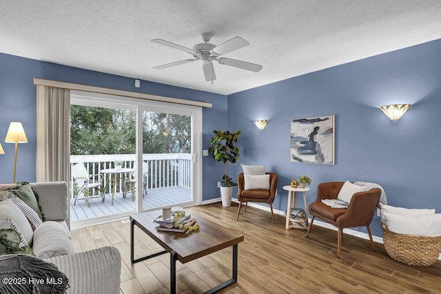 living room featuring ceiling fan, wood-type flooring, and a textured ceiling