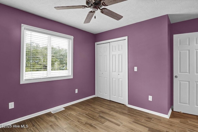 unfurnished bedroom with a closet, ceiling fan, hardwood / wood-style floors, and a textured ceiling