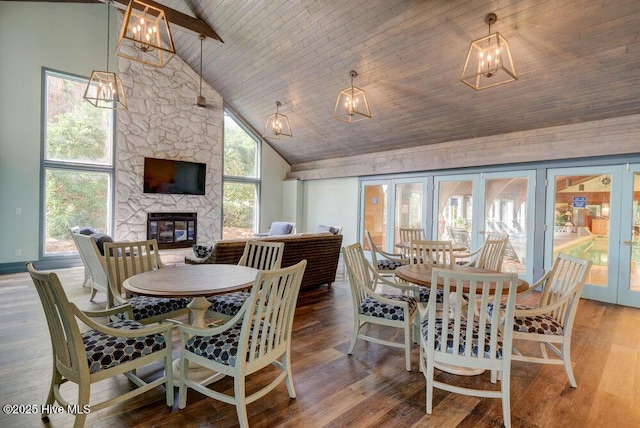 dining area with french doors, high vaulted ceiling, a wealth of natural light, and a fireplace