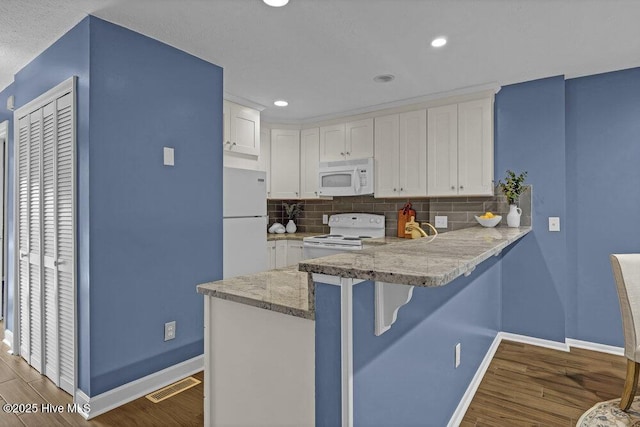 kitchen featuring white cabinets, hardwood / wood-style flooring, white appliances, and tasteful backsplash