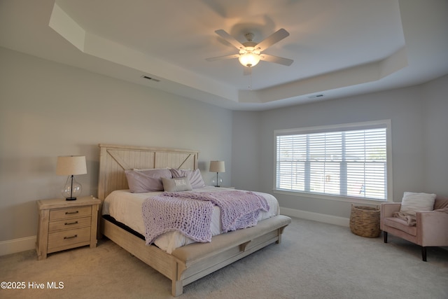 carpeted bedroom featuring a raised ceiling and ceiling fan