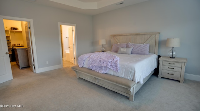 bedroom with connected bathroom, a walk in closet, and light colored carpet