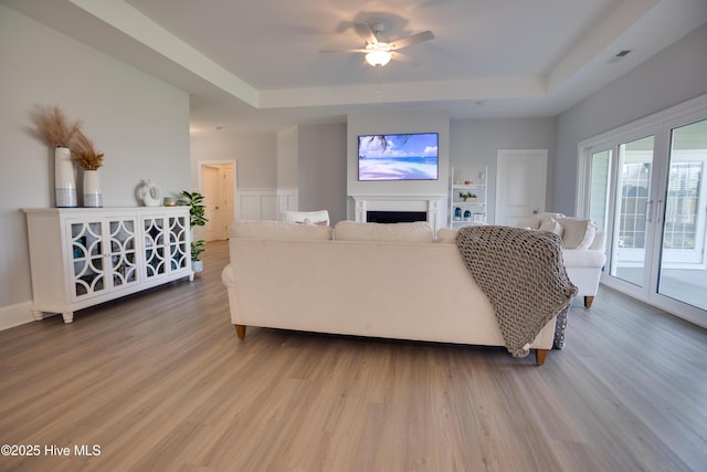 living room with hardwood / wood-style flooring, ceiling fan, french doors, and a tray ceiling