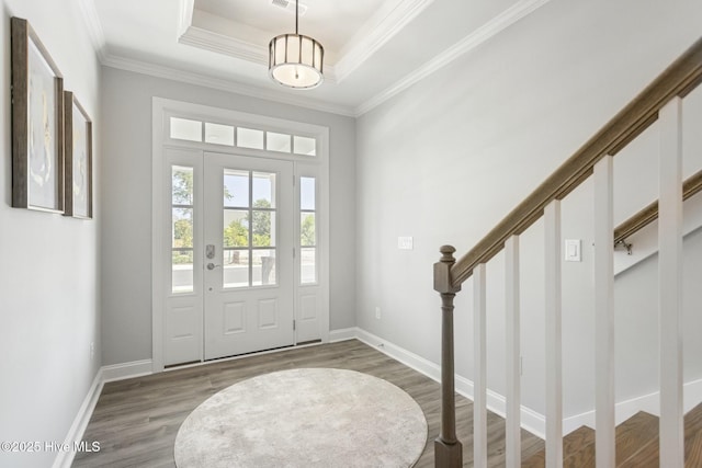 entryway with baseboards, a tray ceiling, wood finished floors, and crown molding