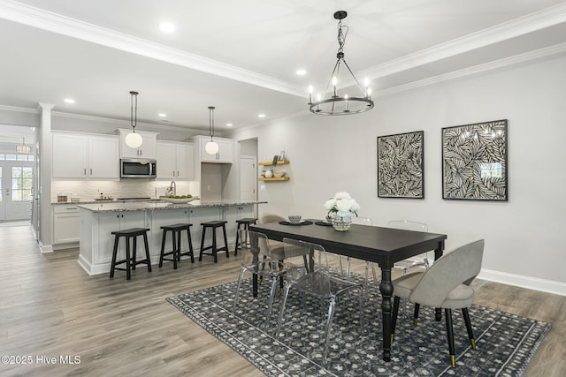 dining room with baseboards, a notable chandelier, ornamental molding, and light wood-type flooring