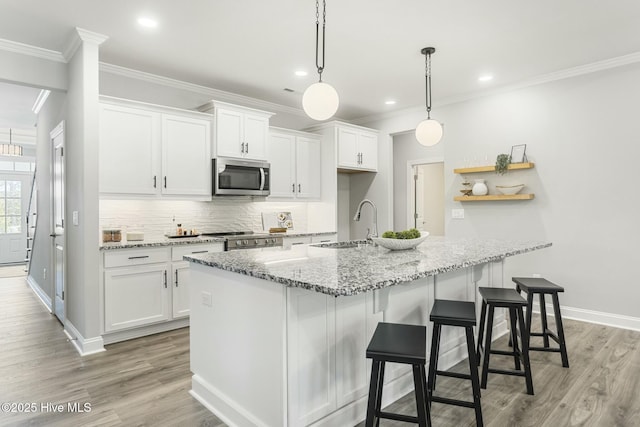kitchen featuring decorative backsplash, white cabinetry, stainless steel appliances, and crown molding