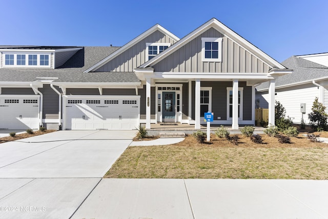 view of front facade with a front lawn, covered porch, and a garage