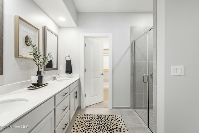full bathroom featuring a shower stall, double vanity, tile patterned flooring, and a sink