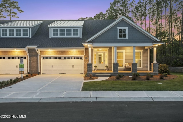 craftsman-style home featuring driveway, covered porch, a garage, and a yard