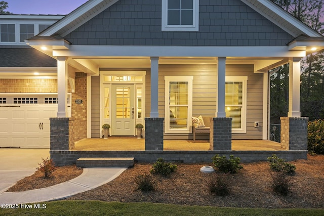 view of front of house featuring driveway, an attached garage, and a porch