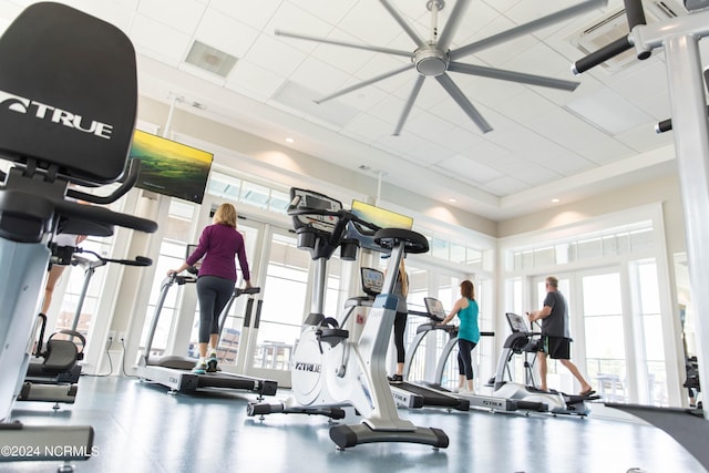 exercise room featuring visible vents, a high ceiling, a healthy amount of sunlight, and a ceiling fan