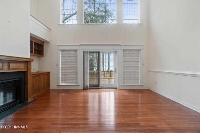 unfurnished living room with hardwood / wood-style floors and a towering ceiling