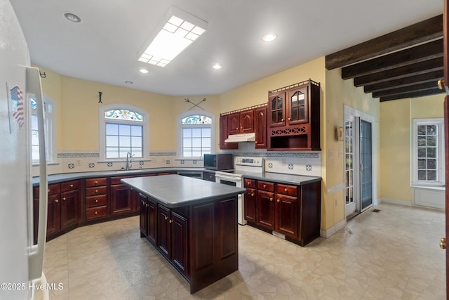 kitchen featuring decorative backsplash, a kitchen island, white appliances, and beam ceiling