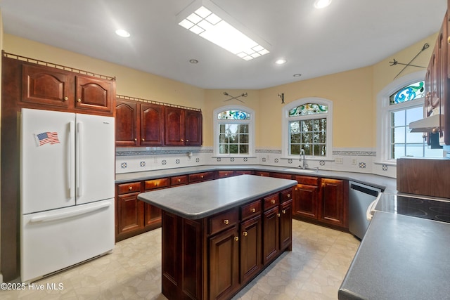 kitchen with backsplash, stainless steel dishwasher, sink, white fridge, and a kitchen island