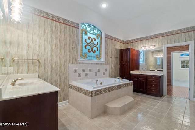 bathroom featuring vanity, a relaxing tiled tub, tile patterned floors, and vaulted ceiling