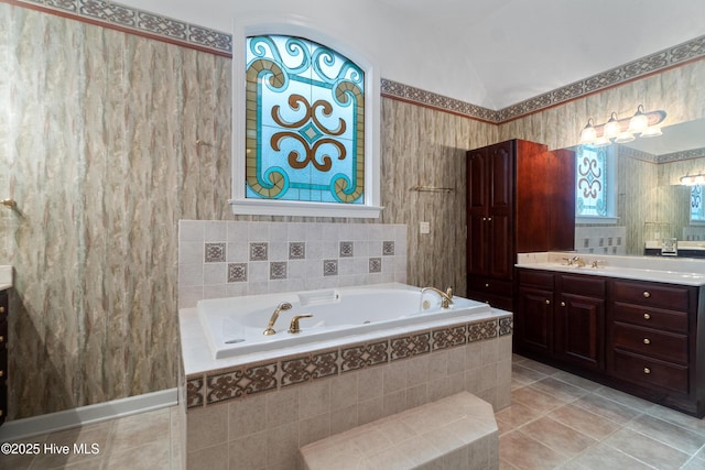 bathroom featuring tile patterned flooring, vanity, tiled bath, and lofted ceiling