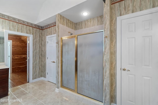 bathroom with a shower with door, lofted ceiling, and tile patterned flooring