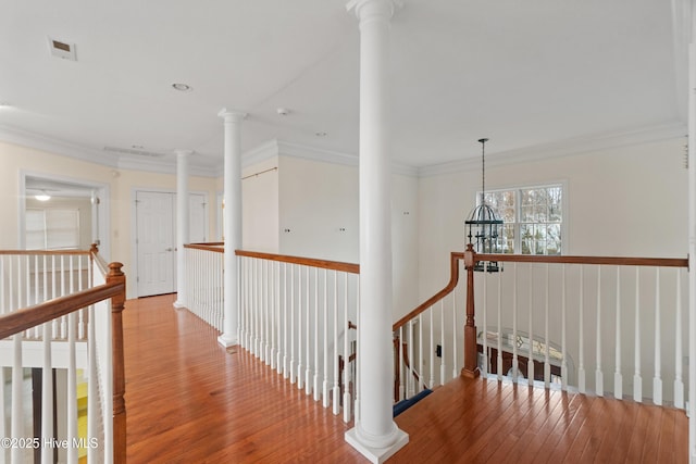 corridor with a notable chandelier, wood-type flooring, and ornamental molding