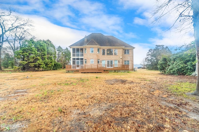 rear view of house featuring a sunroom, a deck, and a yard